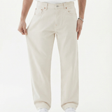 The Jeans Relaxed Straight Fit in ecru — model pulling at the leg to show fabric stretch