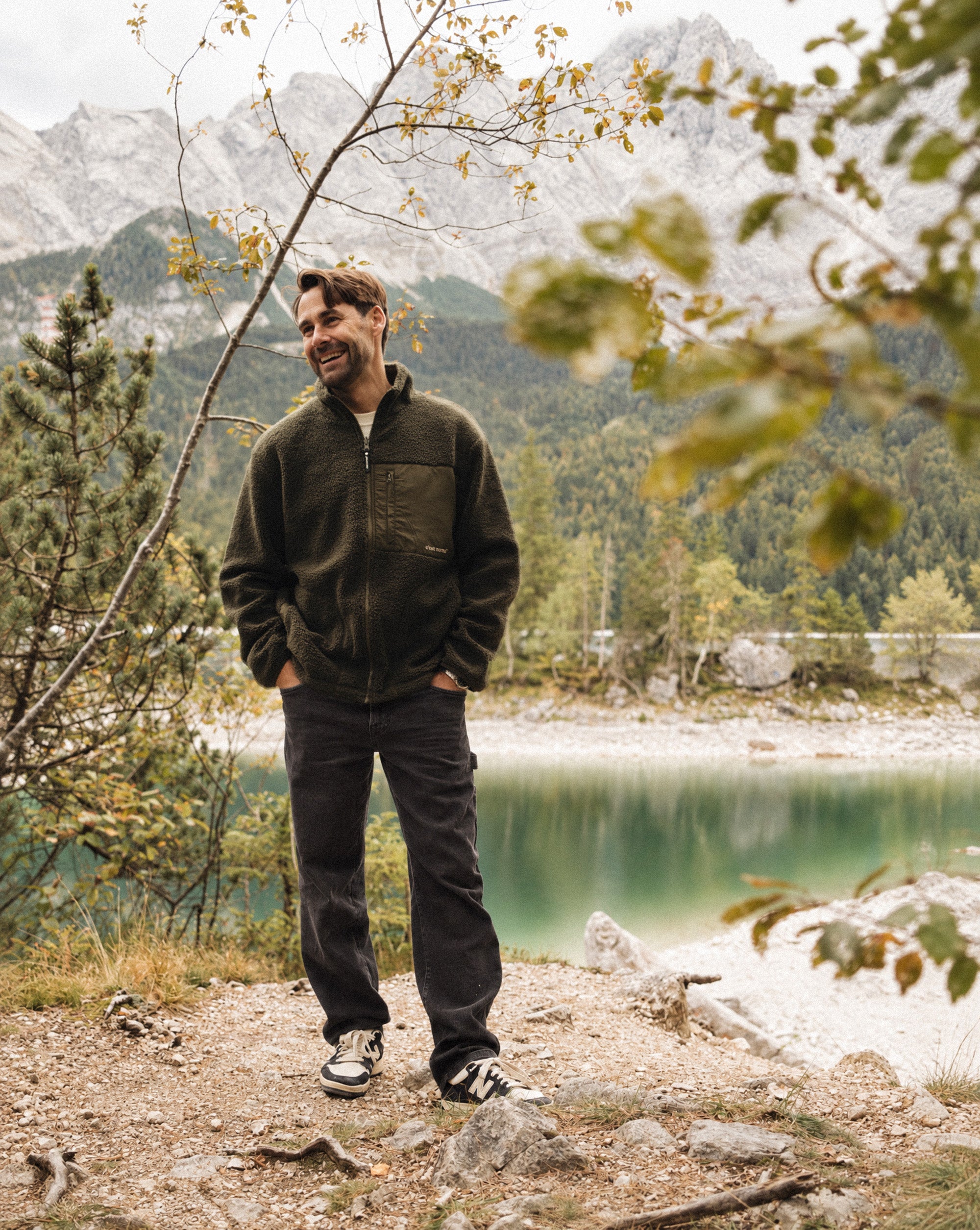 The Lille Cord Carpenter Pant in anthracite — worn outdoors by a lake in the mountains