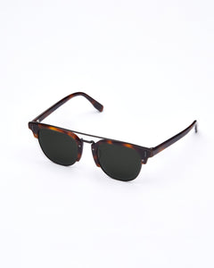 A pair of J90 sunglasses in tortoise, placed on a white background. The image highlights the dark violet lenses, a double bridge design, and the c'est normal text on the temple.