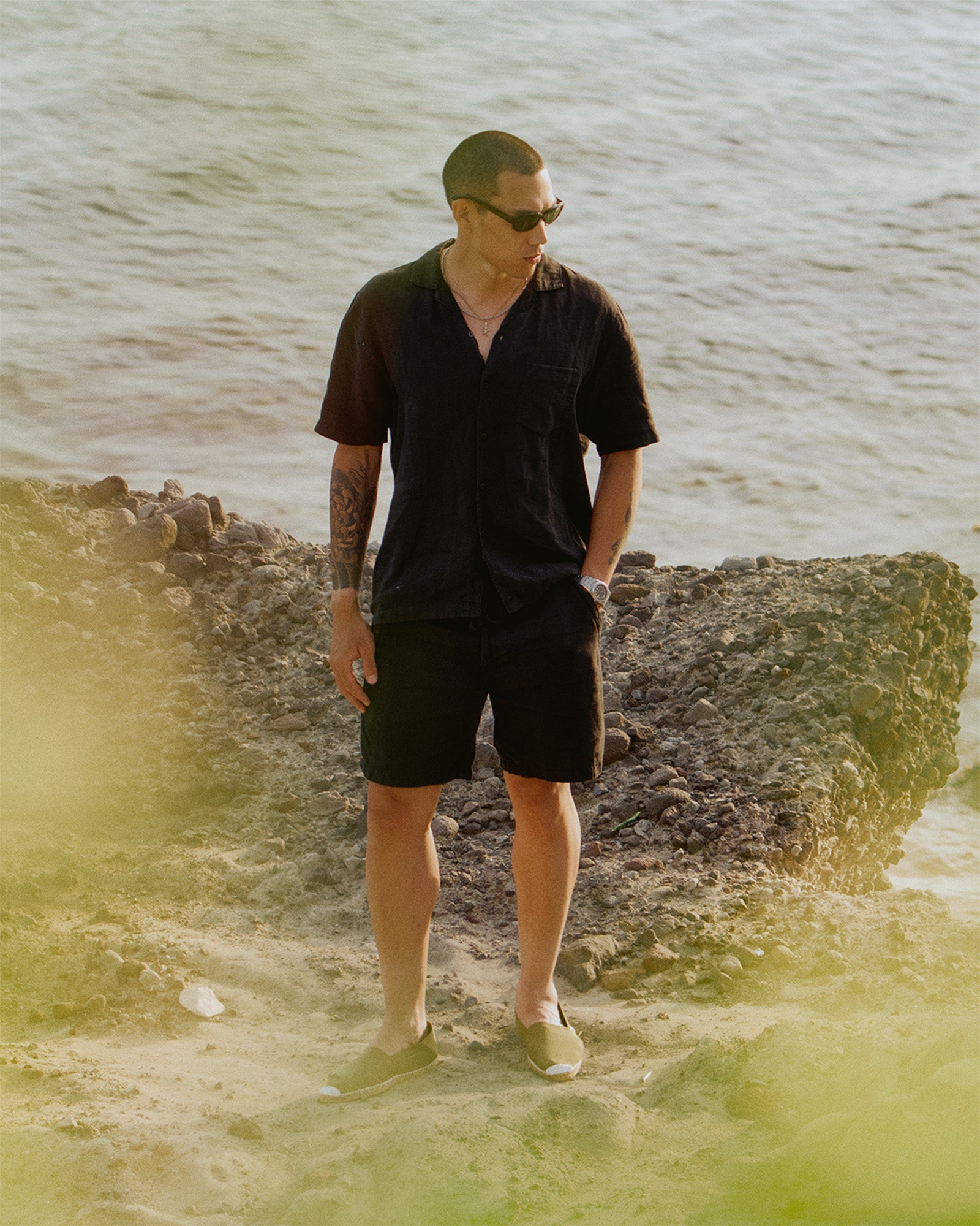 The Holiday Linen Short in black — worn with a matching linen shirt by the sea