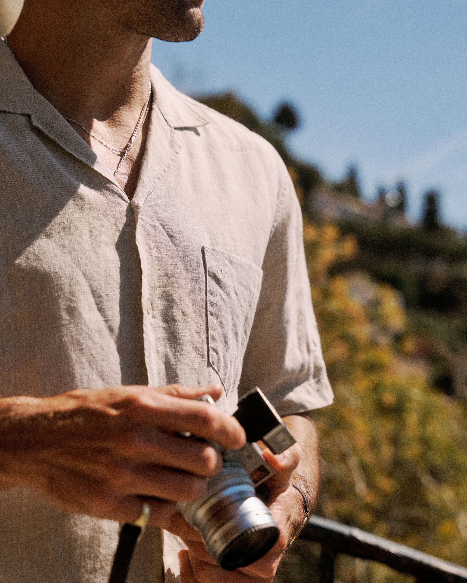 The Holiday Linen SS Shirt in natural — worn while holding a vintage camera
