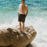 The Board Shorts in khaki — worn while standing on a rock with crashing waves