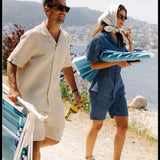 Le Waffle Resort Shirt in light beige — worn while carrying beach chairs on a sunny coastal path