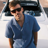 Le Waffle Resort Shirt in azure — worn leaning against a white vintage convertible