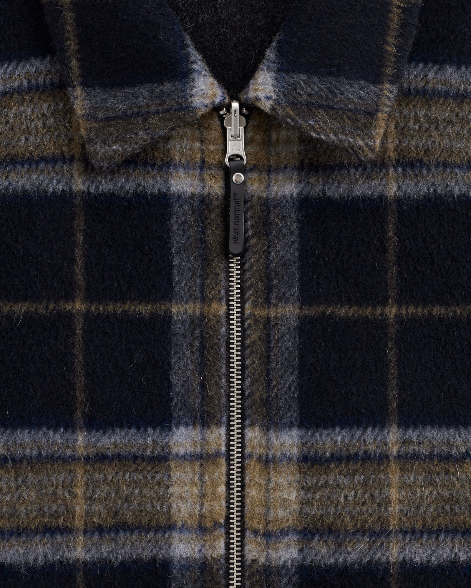 The Reversable Wool Jacket in dark plaid — closeup of the front zipper and collar