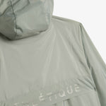A close-up shot of the back of The Running Jacket in Sage Green, laid flat against a white background. The image focuses on the back ventilation panel, hood, and reflective ATHLÉTIQUE branding.