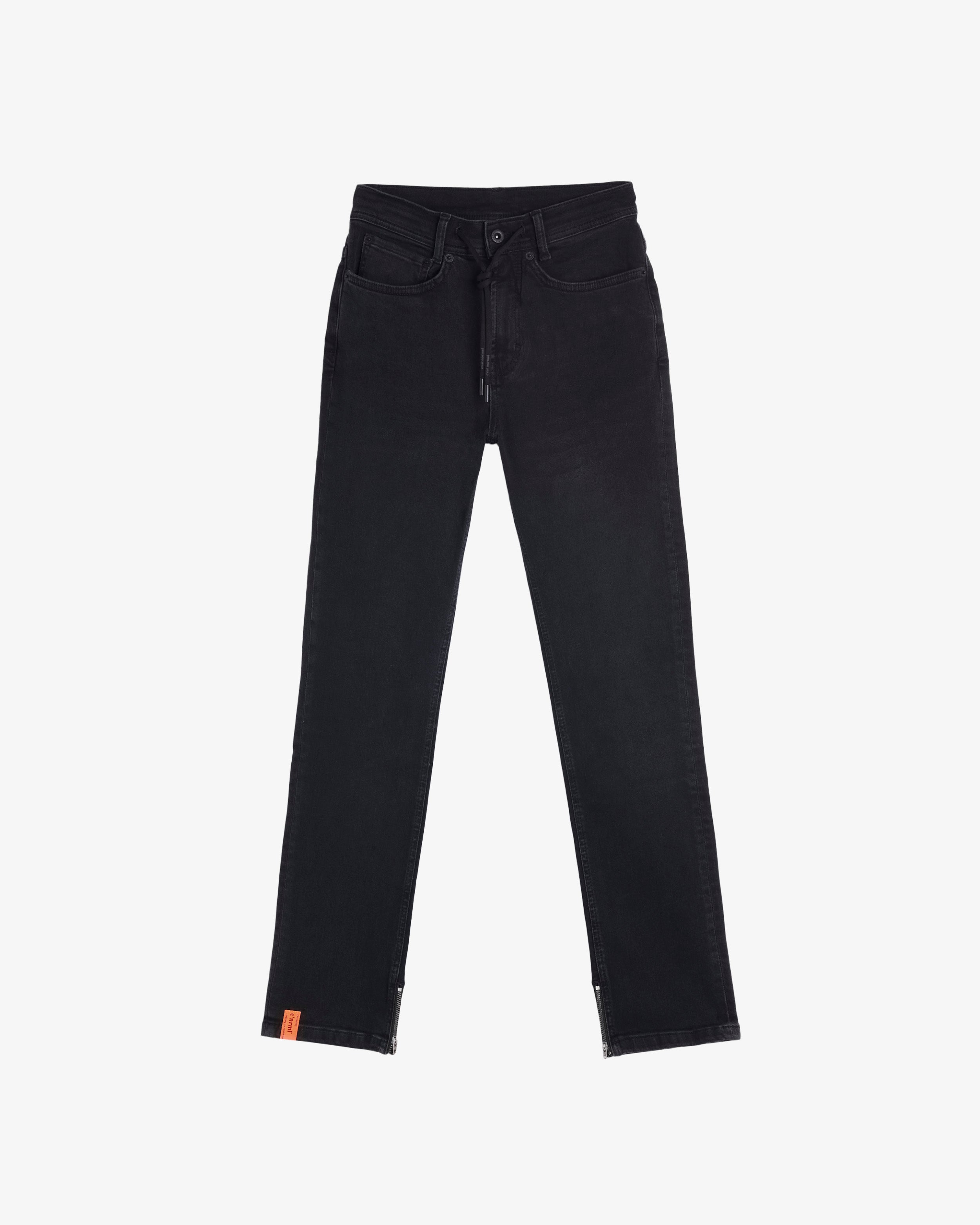 A front view of The Jeans Regular Fit in black, laid flat on a white background. The image highlights the drawstring waist, five-pocket design, ankle zippers, and the orange c'est normal label at the ankle.
