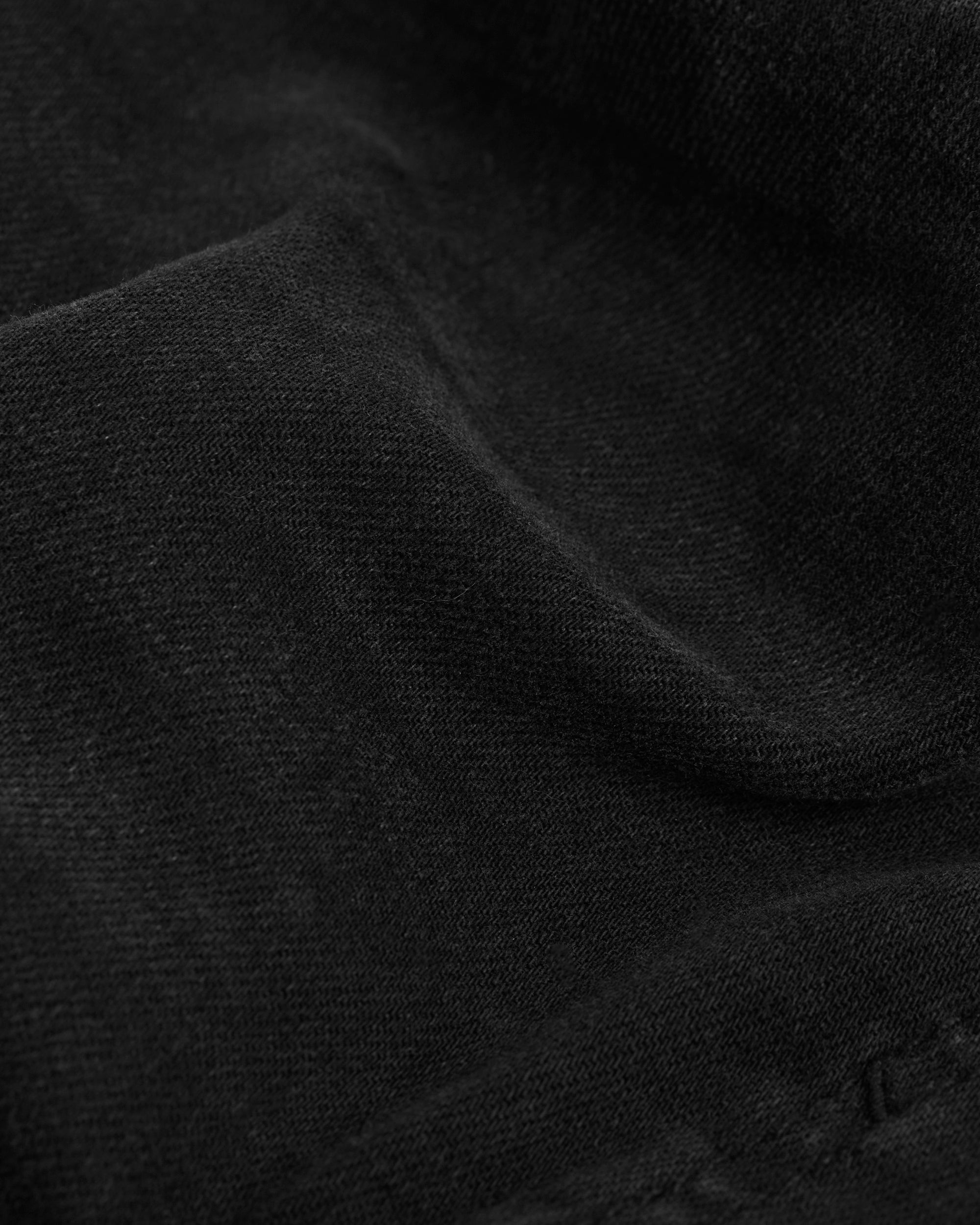 A close-up shot of the soft, broken-in black denim fabric of The Jeans Regular Fit from c'est normal.
