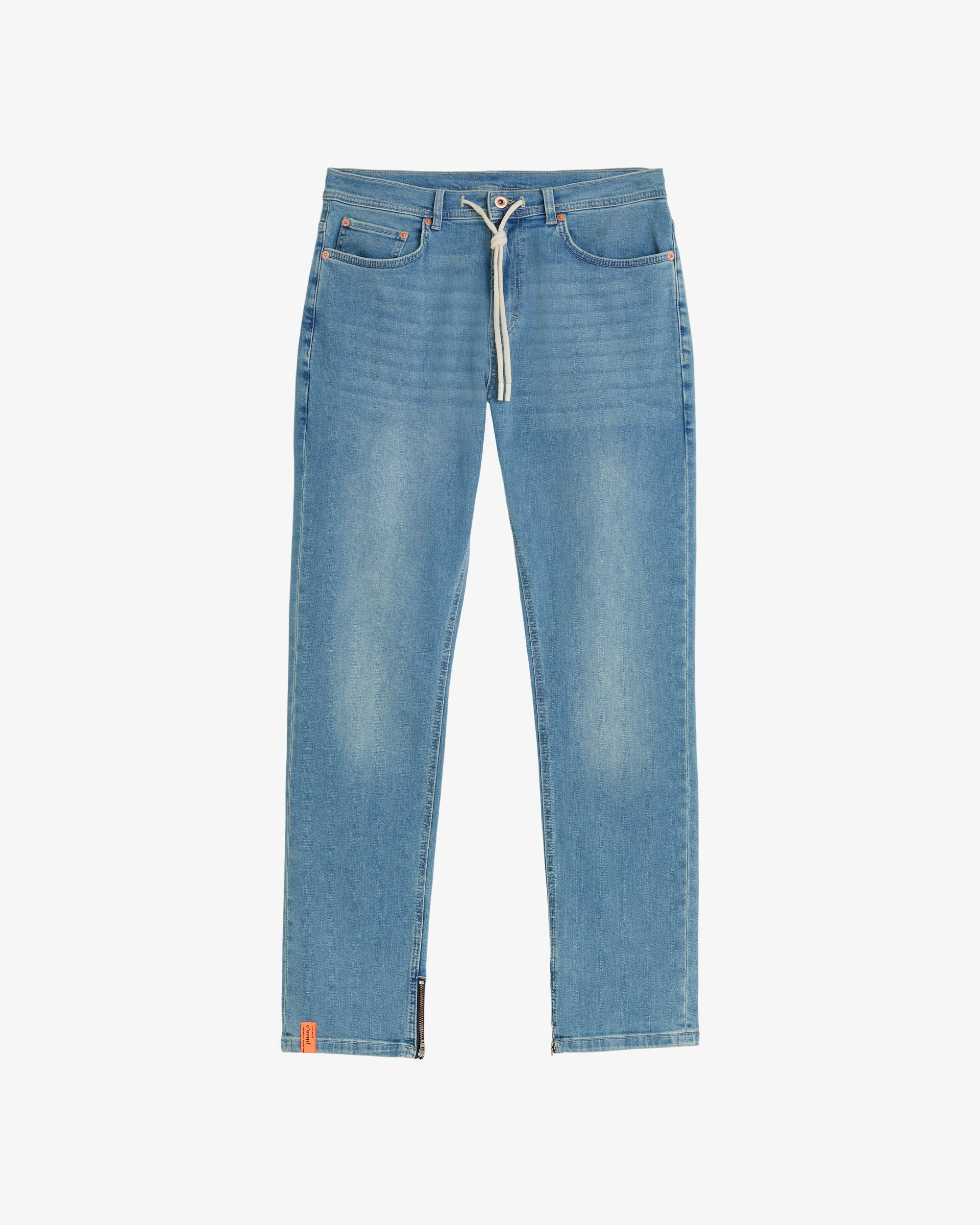 A front view of The Jeans Regular Fit in blue, laid flat on a white background. The image highlights the white drawstring waist, front pockets, ankle zippers, and a small orange c'est normal tag on the bottom hem.