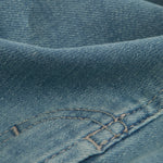 A close-up shot of the blue denim fabric of The Jeans Regular Fit, highlighting the texture and stitching details.