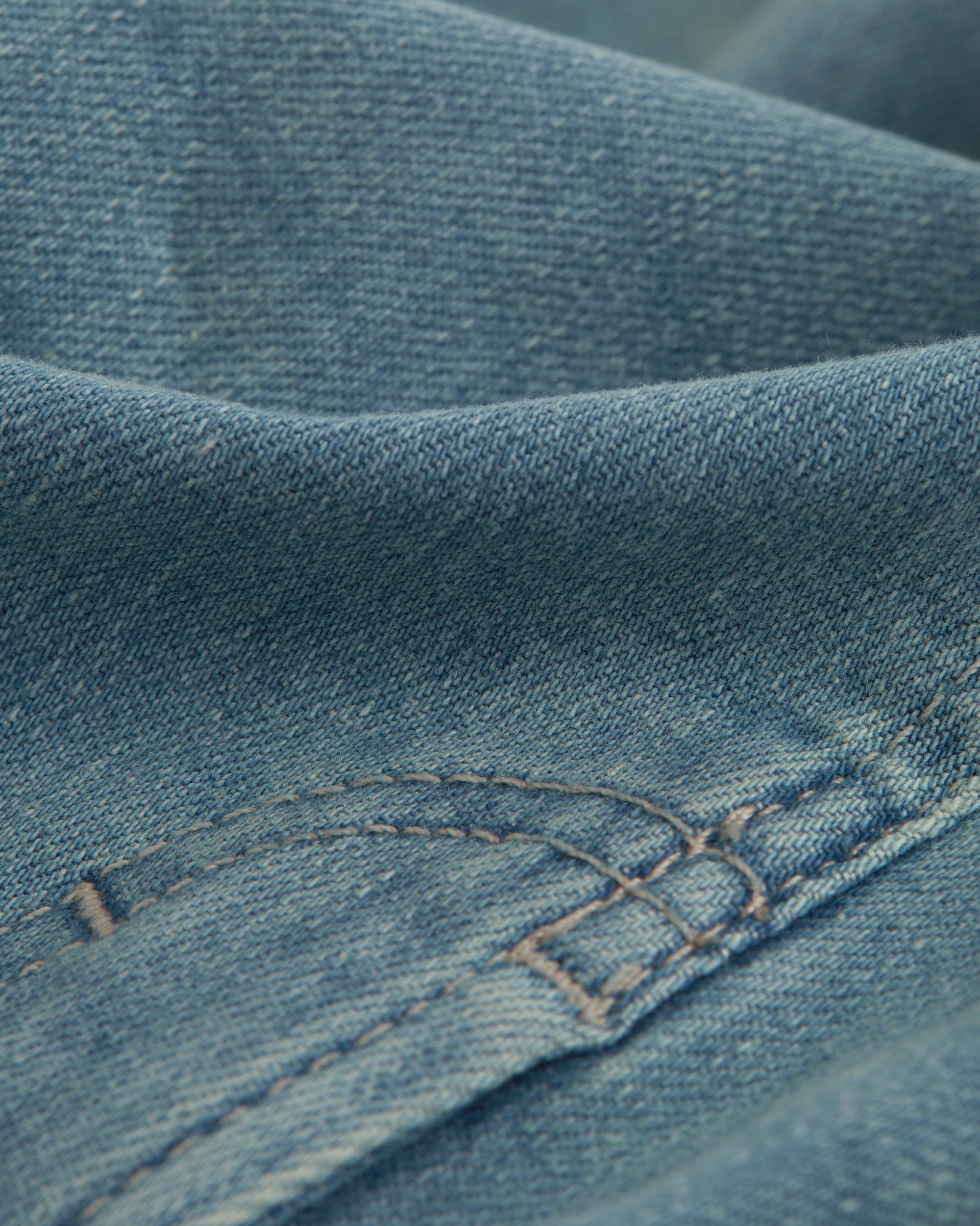 A close-up shot of the blue denim fabric of The Jeans Regular Fit, highlighting the texture and stitching details.