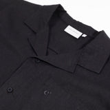 The Linen Resort Shirt in black — close-up of the camp collar and embroidered C' logo