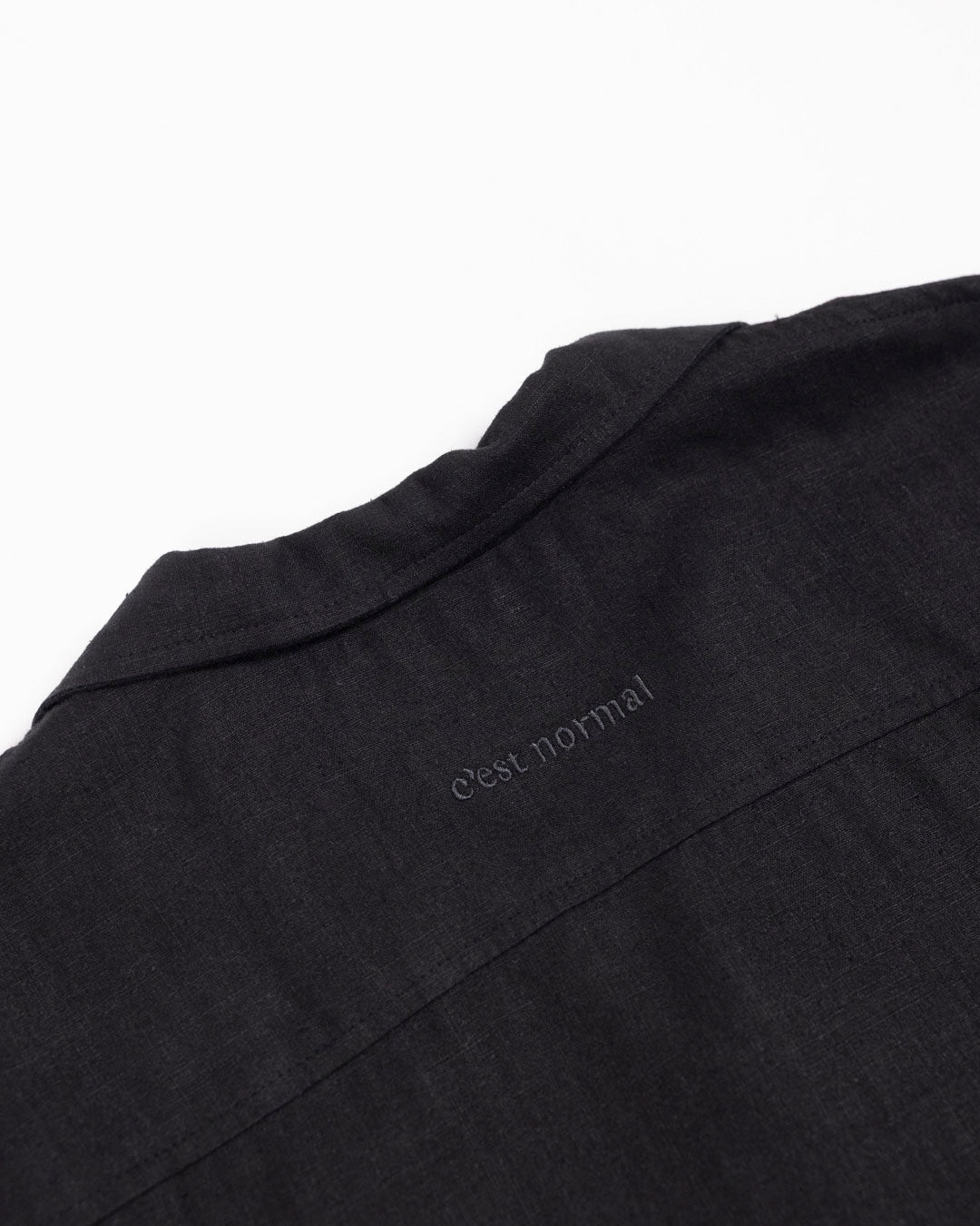 The Linen Resort Shirt in black — back yoke with tonal C'est normal embroidery