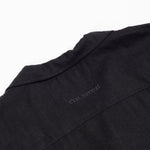 The Linen Resort Shirt in black — back yoke with tonal C'est normal embroidery