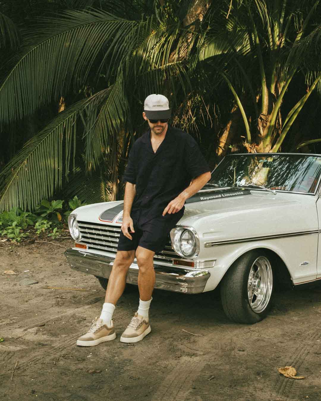 The Linen Resort Shirt in black — worn while leaning against a white vintage car