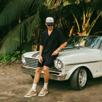 The Linen Resort Shirt in black — worn while leaning against a white vintage car