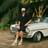 The Linen Resort Shirt in black — worn while leaning against a white vintage car