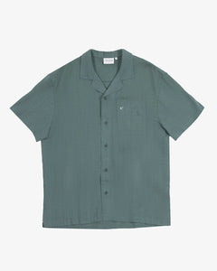 The Linen Resort Shirt in sage — flat lay with camp collar and chest pocket