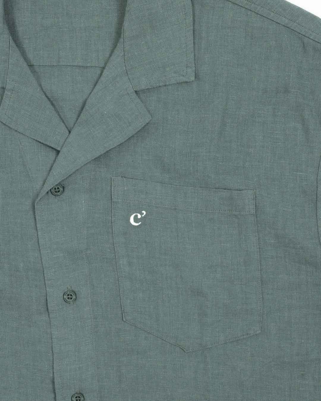 The Linen Resort Shirt in sage — close-up of the chest pocket with an embroidered white logo
