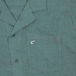 The Linen Resort Shirt in sage — close-up of the chest pocket with an embroidered white logo