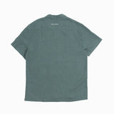 The Linen Resort Shirt in sage — back view with C'est normal embroidery on the yoke
