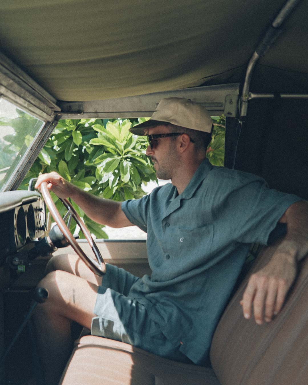 The Linen Resort Shirt in sage — worn while sitting in the driver's seat of a vintage vehicle