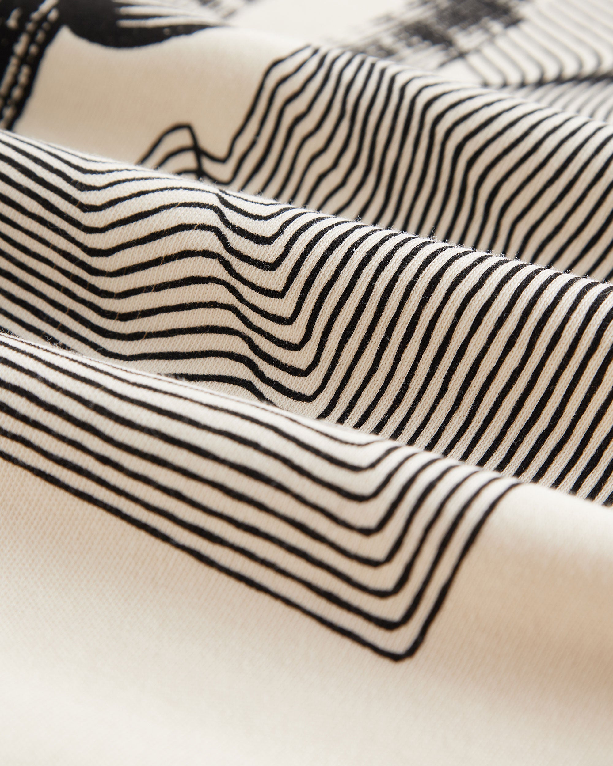 The Oversized Printed T-shirt in cream and black — close-up of the geometric line print