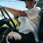 The Tampah Hills Linen Resort Shirt in cream — worn while driving an off-road vehicle