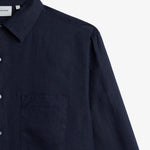 The Daily Linen Shirt in navy — close-up of the chest pocket with tonal embroidery