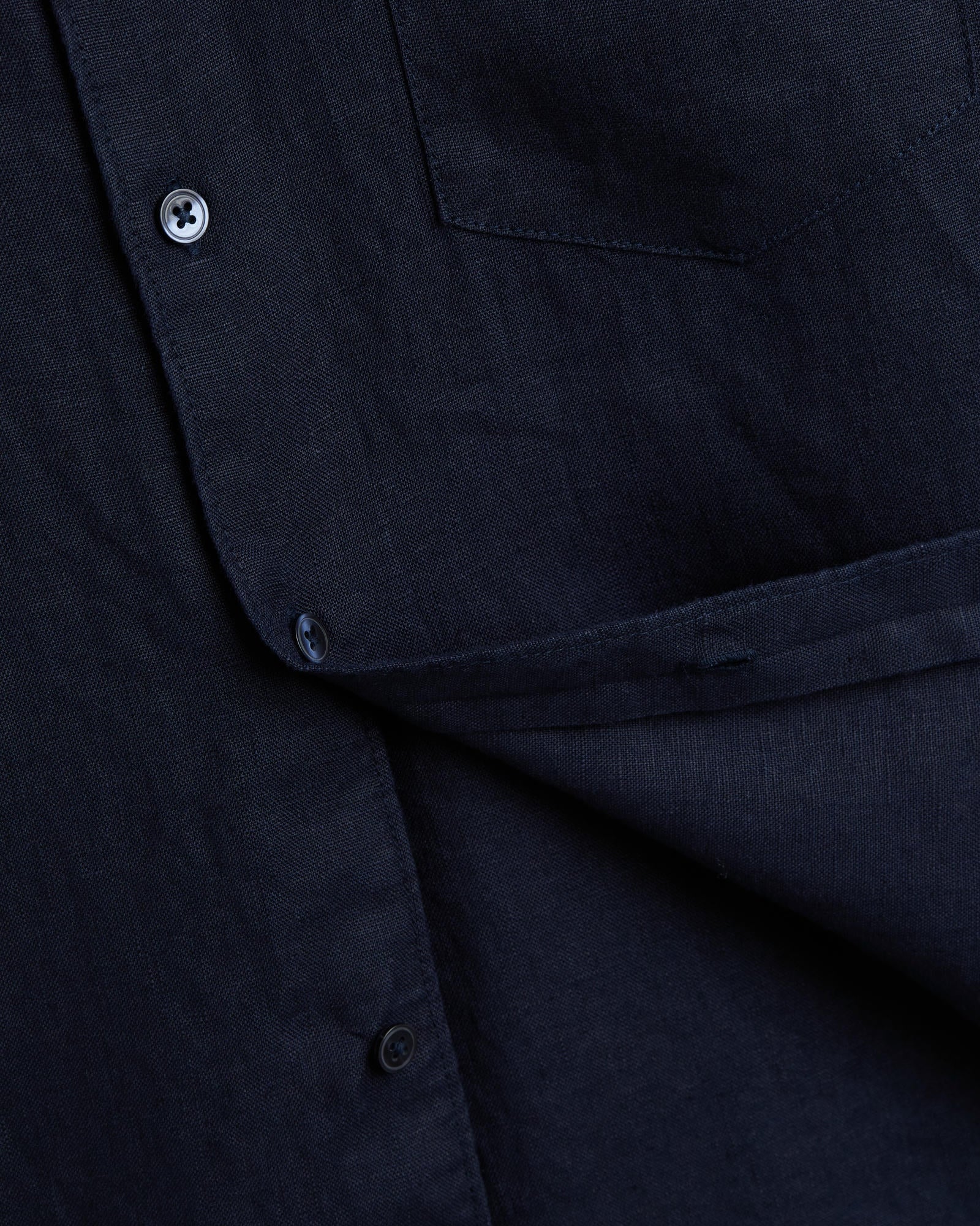 The Daily Linen Shirt in navy — close-up showing the linen texture and button placket