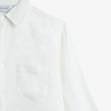 The Daily Linen Shirt in off white — close-up showing the chest pocket and tonal embroidery