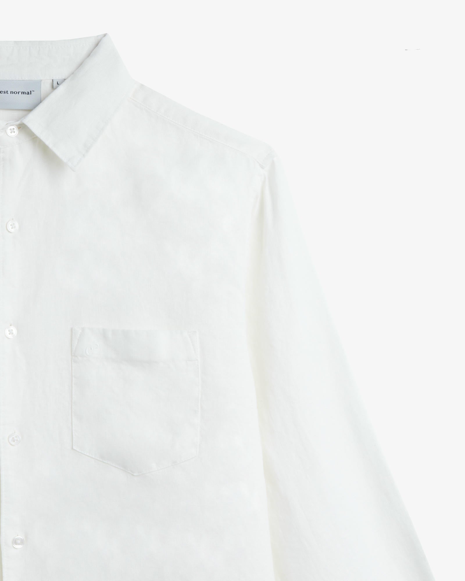 The Daily Linen Shirt in off white — close-up showing the chest pocket and tonal embroidery