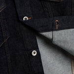 The Denim Jacket in rinse blue — close-up of silver shank buttons engraved with C'est normal