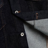 The Denim Jacket in rinse blue — close-up of silver shank buttons engraved with C'est normal