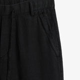 The Holiday Linen Trouser in black — close-up of the waistband and tonal C'est normal embroidery