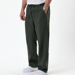 The Holiday Linen Trouser in dark khaki — worn with white sneakers