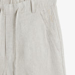 The Holiday Linen Trouser in natural — close-up of the waistband and embroidered logo