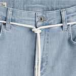 A close-up view of the front waistband of The Jeans Skinny Fit in light blue, featuring a white drawstring tied at the center and a branded c'est normal button.