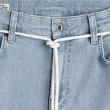 A close-up view of the front waistband of The Jeans Skinny Fit in light blue, featuring a white drawstring tied at the center and a branded c'est normal button.