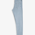 The Jeans Skinny Fit in light blue folded in half, laid flat on a white background, revealing the back pocket and the black rubber patch at the back waist with the c'est normal logo.