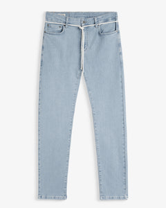 A front view of The Jeans Skinny Fit in Light Blue, laid flat on a white background. The image highlights the classic denim look with a custom shoelace belt and subtle orange accent stitching from c'est normal.