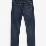 A back view of The Jeans Skinny Fit in Midwash, laid flat on a white background. The image highlights the two back pockets and the black rubber patch with the c'est normal logo at the waist.