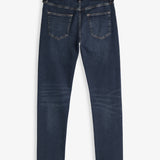 A back view of The Jeans Skinny Fit in Midwash, laid flat on a white background. The image highlights the two back pockets and the black rubber patch with the c'est normal logo at the waist.