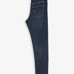 The Jeans Skinny Fit in Midwash folded in half and laid flat on a white background, highlighting the back pocket and the black rubber patch with the c'est normal logo on the waist.