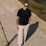 The Sanremo Linen Tee in anthracite grey — worn with cream trousers and sunglasses outdoors
