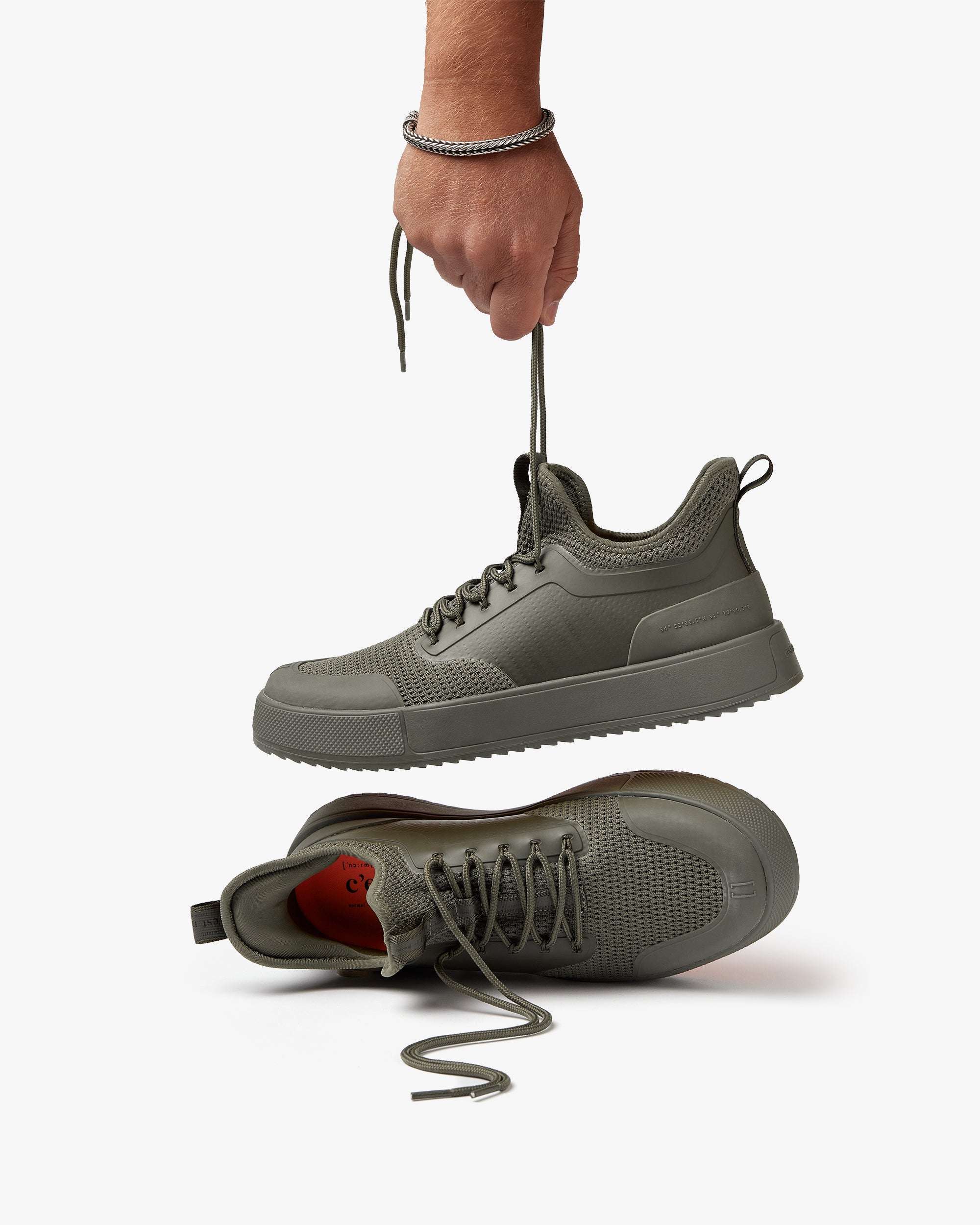The Sneakers 2.0 in khaki — being held up by the laces