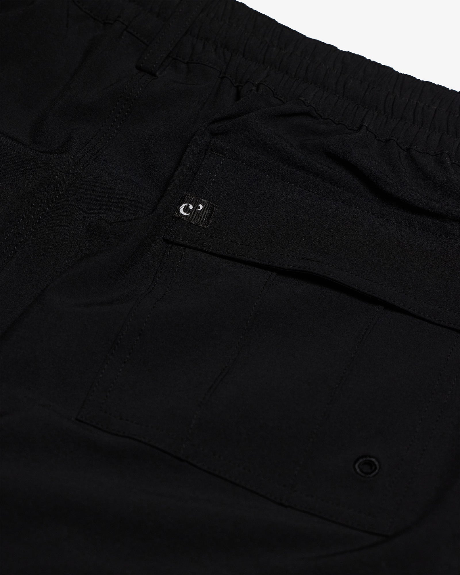 The Board Shorts in black — back pocket detail with a small logo tag and drainage eyelet