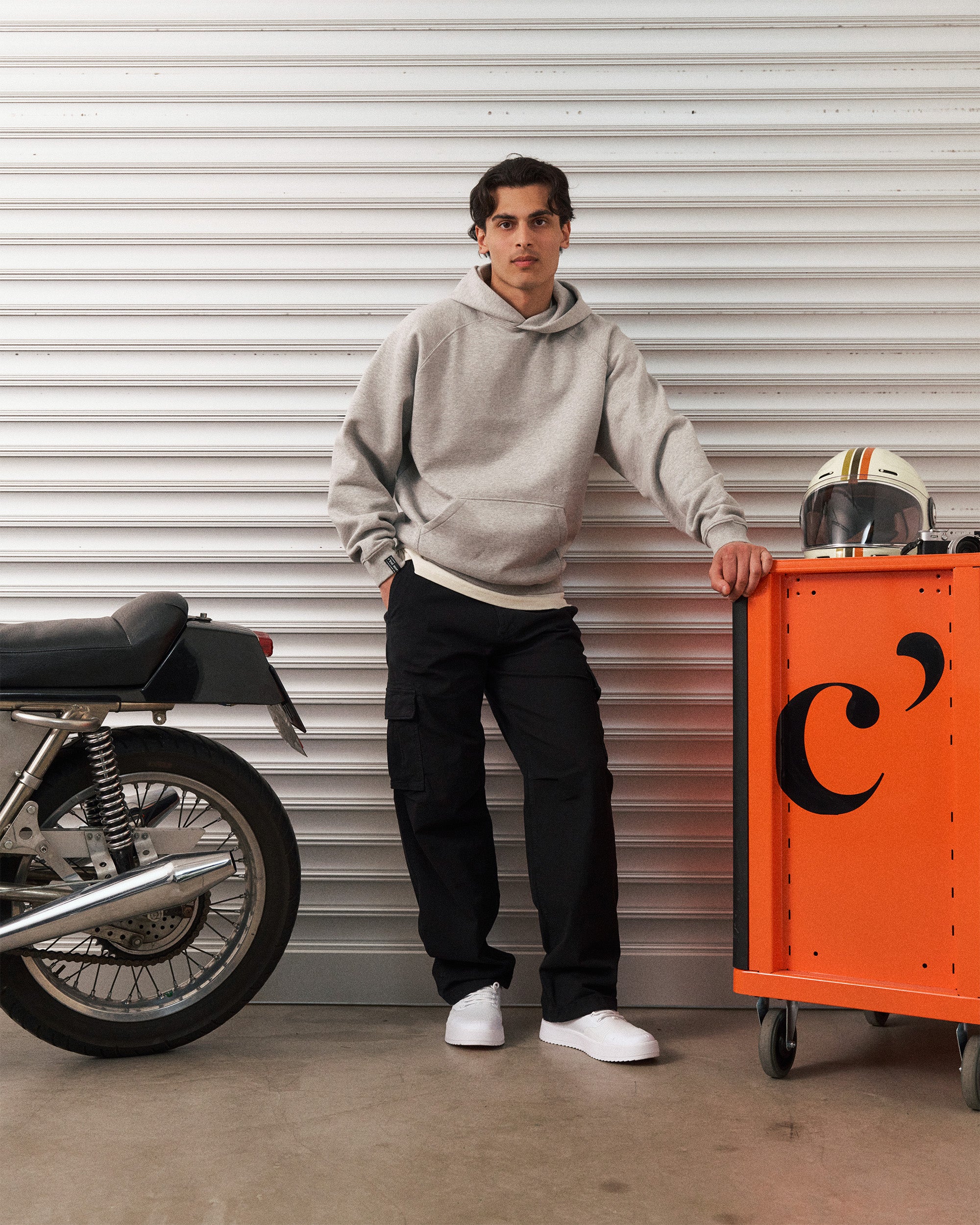 The Monterey Cargo Pant in black — worn with a grey hoodie next to a motorcycle