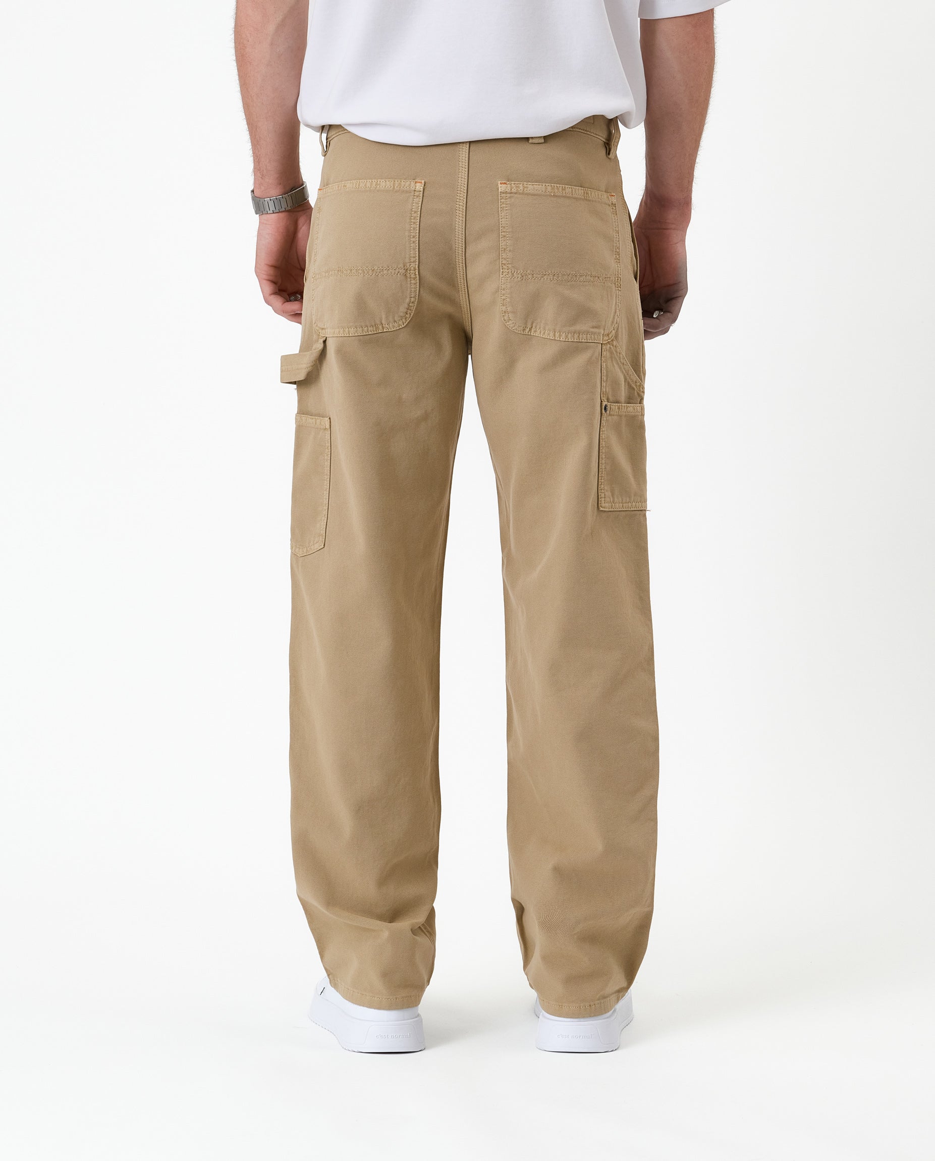 The Carpenter Pant in beige — back view showing utility pockets and hammer loop