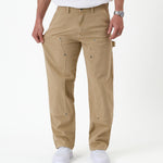 The Carpenter Pant in beige — showing the stretch fabric by pulling the leg